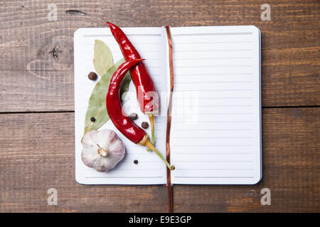 Carta per ricette, pepe e spezie sul tavolo di legno Foto Stock