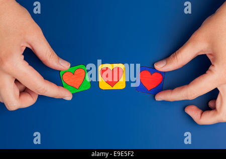 Tre cuori su sfondo blu con la donna con le mani in mano. Cuore disegnato da me. Foto Stock