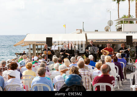 Paphos, Cipro - 24 novembre 2013 persone di ascoltare un concerto live di cucina cipriota tradizionale musica sul lungomare di Paphos. Foto Stock