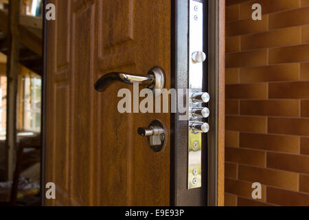 Nuovo acciaio tre vite serratura della porta installata sul legno della porta anteriore di una nuova build house che mostra i tre singoli cilindri di Foto Stock