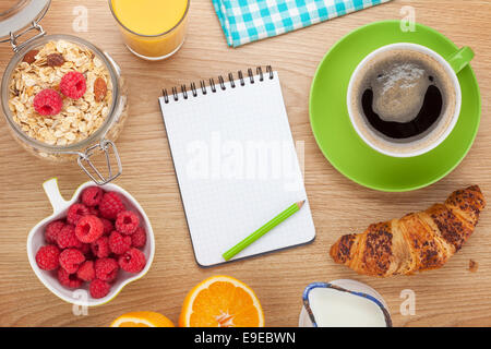 Sana colazione con muesli, frutti di bosco e latte. Sul tavolo di legno con il blocco note per lo spazio di copia Foto Stock