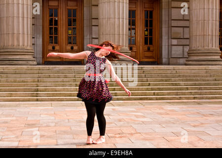 Claire Nicoll hula hoop dancing in un freddo e ventoso ottobre pomeriggio presso l'entrata frontale del Caird Hall di Dundee, Regno Unito Foto Stock