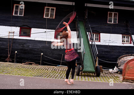 Claire Nicoll hula hoop ballare su un ventoso ottobre giornata accanto al dispositivo HMS Unicorn 1800's fregata a Victoria Dock a Dundee, Regno Unito Foto Stock