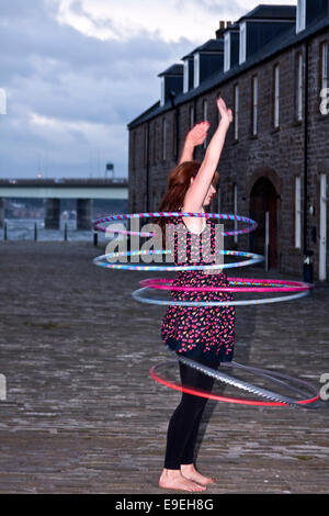 Claire Nicoll hula hoop dancing in un freddo e ventoso ottobre pomeriggio presso il Victoria Docks, City Quay a Dundee, Regno Unito Foto Stock