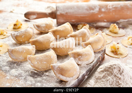 Vareniki canederli con patate e cipolla. Non cotti sulla scrivania in legno. Foto Stock