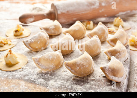 Vareniki canederli con patate e cipolla. Non cotti sulla scrivania in legno. Foto Stock