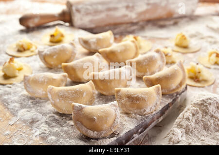 Vareniki canederli con patate e cipolla. Non cotti sulla scrivania in legno. Foto Stock