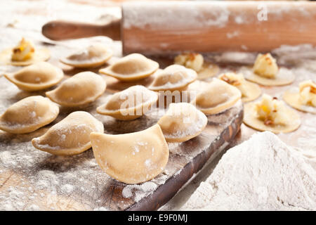 Vareniki canederli con patate e cipolla. Non cotti sulla scrivania in legno. Foto Stock