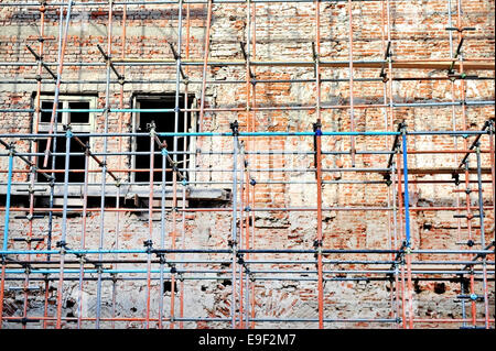 Ponteggio intorno a un edificio di mattoni di facciata ristrutturazione Foto Stock