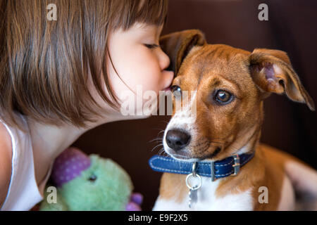 Il Toddler ragazza baciare il suo cucciolo di cane Foto Stock
