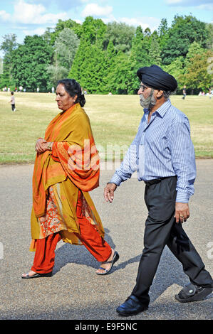 Una vecchia coppia Sikh nel tradizionale abito indiano, a piedi attraverso un parco a Londra, Inghilterra, Regno Unito. Foto Stock