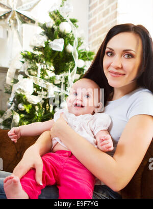 Sorridenti madre con la figlia vicino all'albero di Natale Foto Stock