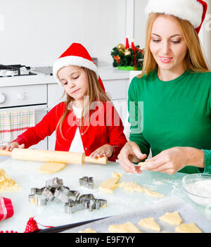 Adorabile ragazza con sua madre la cottura biscotti di Natale in cucina Foto Stock