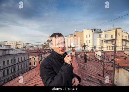 Giovane uomo caucasico fuma sigaro sul tetto nella parte centrale di San Pietroburgo, Russia Foto Stock