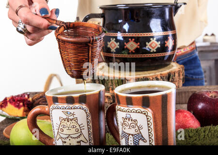 Womans versa manualmente dalla tazza di tè per il tè attraverso un filtro in due tazze di tè, un autunno piacevole decorazione con frutta e c Foto Stock