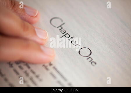 Donna di mano sulla pagina del libro con il titolo 'Capitolo'. Profondità di campo. Foto Stock