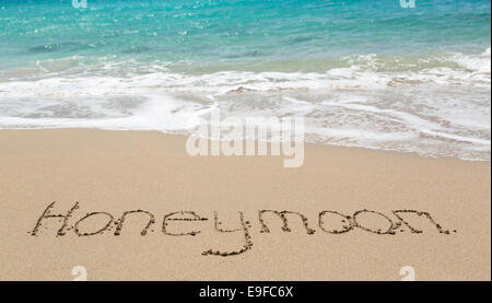 Luna di Miele scritto in sabbia con mare surf Foto Stock