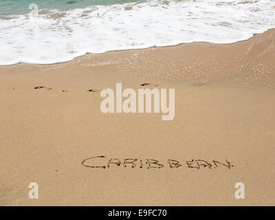 Caraibi scritto in sabbia con mare surf Foto Stock