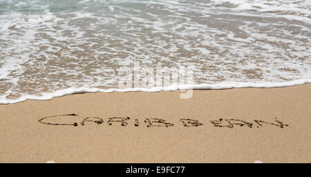 Caraibi scritto in sabbia con mare surf Foto Stock