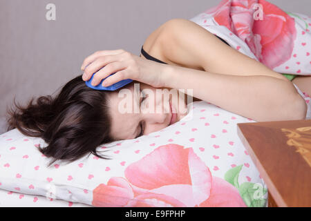 La donna dorme nel letto, in piedi accanto a una sveglia sul tavolo, i luoghi sull'ore sei Foto Stock