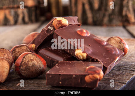 Vicino la pila di delizioso cioccolato al latte pezzi con le nocciole su tavolo in legno, stile retrò Foto Stock