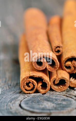 Bastoncini di cannella in cucchiaio sul vecchio sfondo di legno Foto Stock