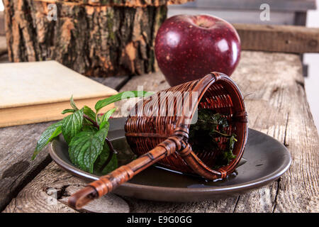 Close up interessante succhieruola vintage su una piastra su un tavolo di legno con il vecchio libro e apple accanto alla decorazione di autunno Foto Stock