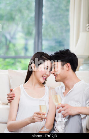 Allegro coppia giovane bevendo champagne in salotto Foto Stock