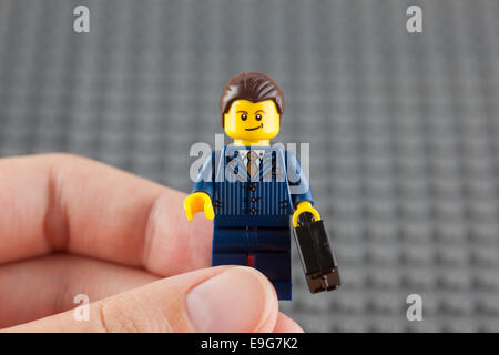 Tambov, Federazione Russa - Giugno 21, 2014 imprenditore Lego minifigure in tuta blu con il nero valigia in mano umana. Foto Stock