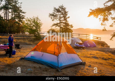 La donna gode di caffè del mattino a lato oceano campeggio, Ruckle Parco Provinciale, sale spring Island, British Columbia, Canada Foto Stock