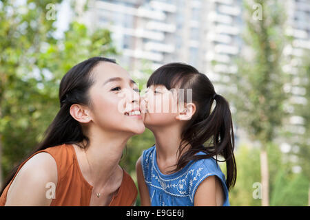 Piccola ragazza baciare la madre Foto Stock