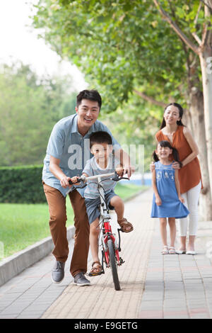 Giovane padre insegnare a suo figlio di andare in bicicletta Foto Stock