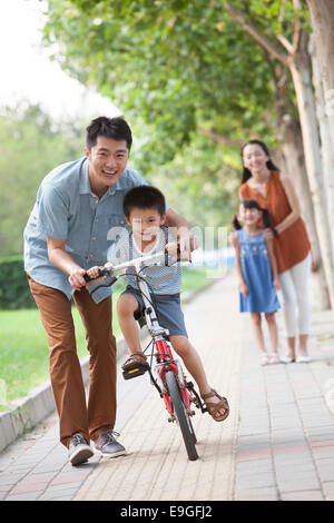 Giovane padre insegnare a suo figlio di andare in bicicletta Foto Stock