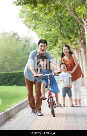 Giovane padre ad insegnare la sua figlia ad andare in bicicletta Foto Stock