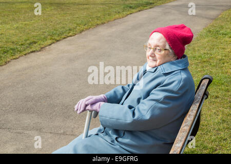 Novantenne signora seduta su una panchina nel parco in autunno. In Inghilterra. Regno Unito Foto Stock