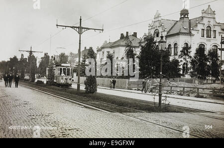 Questa cartolina storica presenta Kirkeveien a Kristiania (ora Oslo), che mostra la scena di strada dei primi anni del XX secolo. L'immagine cattura l'atmosfera urbana trafficata, con tram e pedoni che si muovono lungo la strada, offrendo uno sguardo sulla vita cittadina di Oslo in quel momento. Foto Stock