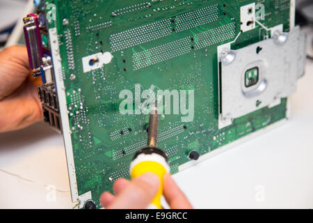 L'uomo facendo le riparazioni su una scheda a circuito stampato con un ferro da saldatore Foto Stock