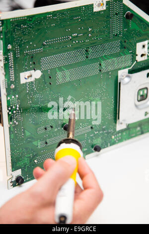 L'uomo facendo le riparazioni su una scheda a circuito stampato con un ferro da saldatore Foto Stock