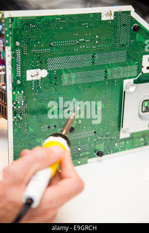 L'uomo facendo le riparazioni su una scheda a circuito stampato con un ferro da saldatore Foto Stock