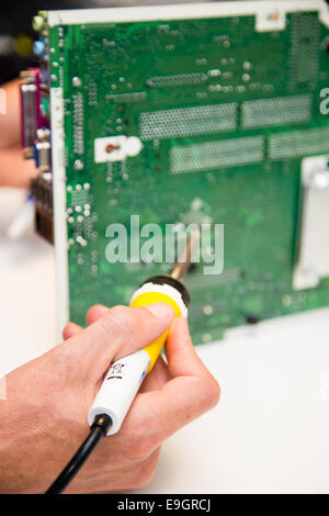 L'uomo facendo le riparazioni su una scheda a circuito stampato con un ferro da saldatore Foto Stock