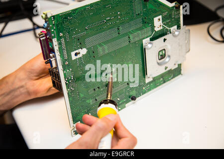 L'uomo facendo le riparazioni su una scheda a circuito stampato con un ferro da saldatore Foto Stock