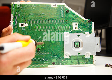 L'uomo facendo le riparazioni su una scheda a circuito stampato con un ferro da saldatore Foto Stock