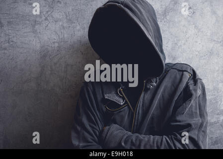 Volto sconosciuto e irriconoscibile uomo con cappa in camera oscura, spooky persona criminale. Foto Stock