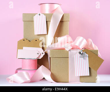 Moderna tendenza naturale di confezione regalo con marrone naturale carta kraft caselle e rosa pallido con nastro bianco e rosa tag regalo Foto Stock