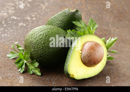 Fresche biologiche mature di avocado con foglie di prezzemolo Foto Stock