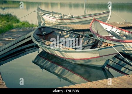 Floating barche di legno con le pale e la sua riflessione in un'acqua. Retrò Tiro filtrato Foto Stock