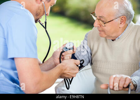 Infermiere controllando la pressione del sangue di uomo senior Foto Stock