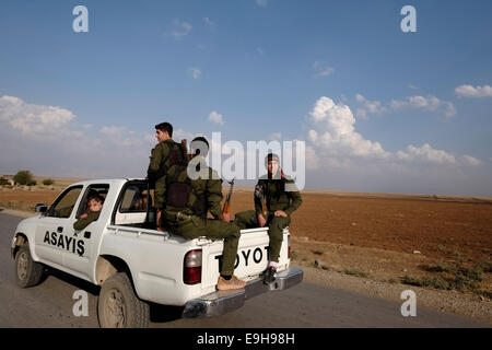 Membri armati del le forze di sicurezza interna noto anche come Asayish Asayis o delle regioni autonome all'interno della lingua curda amministrazione autonoma del nord ed est della Siria a cui spesso viene fatto riferimento come Rojava cavalcare un open-backed Toyota pickup truck in Al Hasakah o Hassakeh nella Siria settentrionale Foto Stock