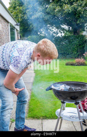 Giovani maschi adulti cercando di luce di un barbecue in estate Foto Stock