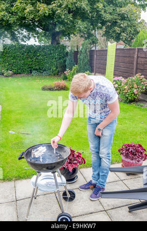 Giovani maschi adulti cercando di luce di un barbecue in estate Foto Stock